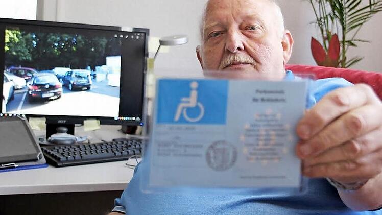 Klaus Bilstein zeigt seinen hellblauen Behinderten-Ausweis. Damit darf er als außergewöhnlich Gehbehinderter auf einem Behinderten-Parkplatz parken. Im Hintergrund auf dem Bildschirm das Foto des Behinderten-Parkplatzes am Schützenhaus Kronach. Der rechte und freie Platz wurde ihm verwehrt.  Foto: Friedwald Schedel