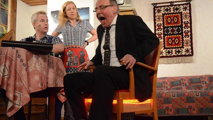 Der verflixte heiße Stuhl erhitzt Gemüter und Gesäß. Dies bekommt hier der Bankdirektor (Stefan Rubel) zu spüren. Er unterbreitet den Werkstattbesitzern (Joachim Blinzler und Claudia Blinzler) keine guten Nachrichten. Foto: Karl-Heinz Hofmann