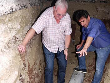 Unter der Straße: Planer Jürgen Kittner (links) und Bürgermeister Rolf Rosenbauer auf einem der alten Grauguss-Rohre, die am Wochenende ausgewechselt werden. Deshalb ist in der Nacht auf Samstag die Wasserversorgung in weiten Teilen der Gemeinde unterbrochen. Foto: Berthold Köhler