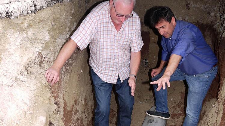 Unter der Straße: Planer Jürgen Kittner (links) und Bürgermeister Rolf Rosenbauer auf einem der alten Grauguss-Rohre, die am Wochenende ausgewechselt werden. Deshalb ist in der Nacht auf Samstag die Wasserversorgung in weiten Teilen der Gemeinde unterbrochen. Foto: Berthold Köhler