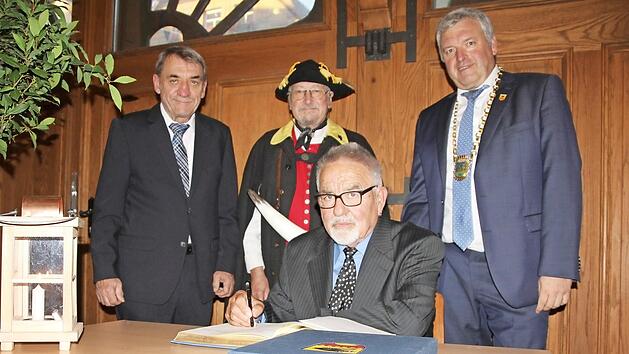 Ins Buch der Stadt trugen sich als neue Tr&auml;ger der B&uuml;rgermedaille Hans Elflein (sitzend) und Armin Dominka ein. Flankiert wurden sie vom Landrats-Stellvertreter Oskar Ebert (links) und B&uuml;rgermeister J&uuml;rgen Hennemann. Dominka wurde von Kollegen aus K&ouml;nigsberg und Bad Rodach begleitet. F&uuml;r den musikalischen Rahmen sorgte das Blasorchester Ebern.&nbsp; Foto: Ralf Kestel