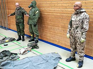 Oberstabsfeldwebel d. R. J&ouml;rg Gaschler demonstriert das An- und Ablegen der pers&ouml;nlichen ABC-Schutzausr&uuml;stung mit zwei Soldaten. Foto: Frank Greif