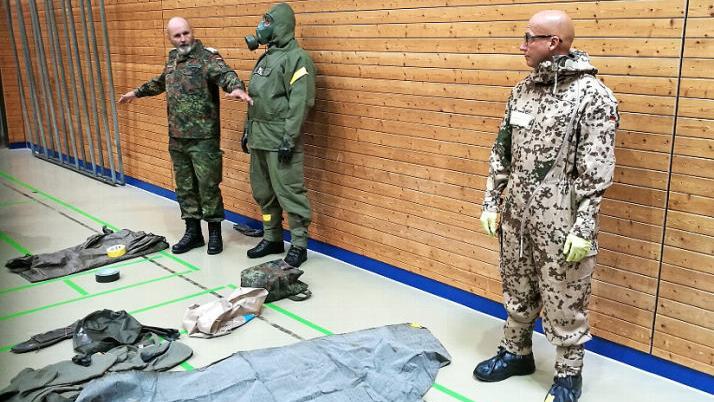 Oberstabsfeldwebel d. R. J&ouml;rg Gaschler demonstriert das An- und Ablegen der pers&ouml;nlichen ABC-Schutzausr&uuml;stung mit zwei Soldaten. Foto: Frank Greif