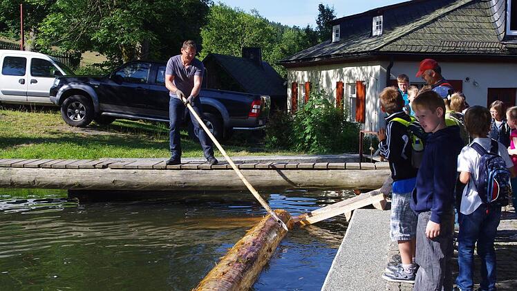 Oliver Bauer (vorne) schaut fasziniert zu, wie Stefan Reif die Baumstämme ans Land befördert. Foto: Heike Schülein