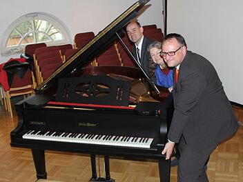 Kaum vom Fleck zu kriegen: Nur durch den Einsatzes eines Kranes kann der VHS-Flügel vom Saal der Raiffeisenbank in Räume der Musikschule im Schumacherhaus transportiert werden, wie Marketingleiter Matthias Batzner, Dr. Karin Meyer-Jungclaussen und Bankdirektor Norbert Knorr bei allergrößter Anstrengung demonstrieren. Foto: Ralf Kestel