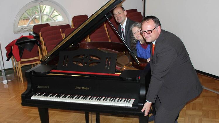 Kaum vom Fleck zu kriegen: Nur durch den Einsatzes eines Kranes kann der VHS-Flügel vom Saal der Raiffeisenbank in Räume der Musikschule im Schumacherhaus transportiert werden, wie Marketingleiter Matthias Batzner, Dr. Karin Meyer-Jungclaussen und Bankdirektor Norbert Knorr bei allergrößter Anstrengung demonstrieren. Foto: Ralf Kestel