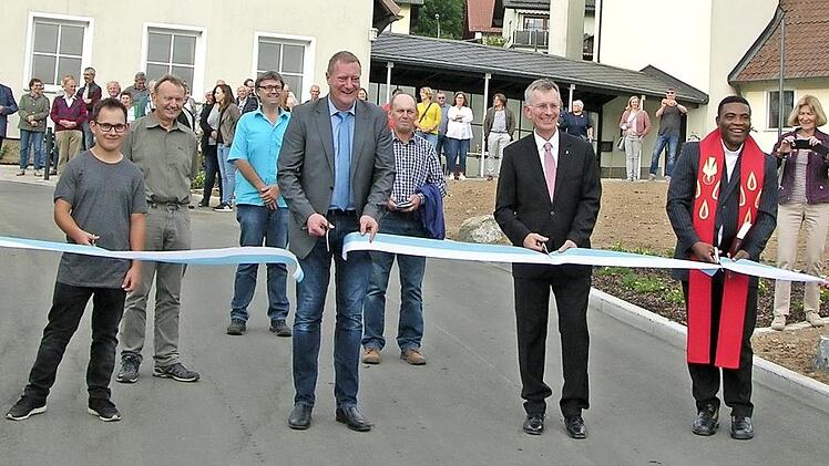 Zahlreiche Zaungäste verfolgten den gemeinsamen Scherenschnitt, mit dem (von links) Jens Kürschner, Bürgermeister Michael Keilich, Pfarrer Dirk Acksteiner und Pater Peter Uzor die östliche Friedhofszufahrt in Sonnefeld ihrer Bestimmung übergaben. Foto: Klaus Oelzner