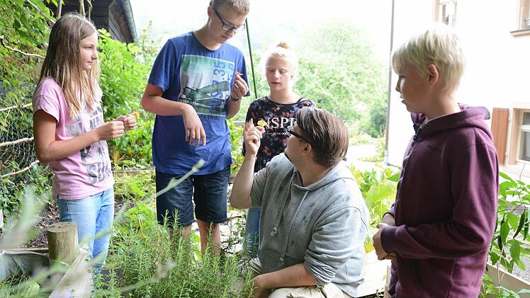 Praktische Kräuterkunde: Erzieher Thomas Schneider mit den gartenbegeisterten Kindern im Kräuterbeet. Foto: Dagmar Besand