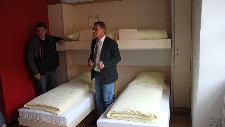 Herbergsvater Hubert Backer (links) und Bürgermeister Wolfgang Beiergrößlein freuen sich über die hochwertige Möblierung im Westflügel der Festungsherberge. Das obere Bett kann nach oben geklappt, die beiden unteren Betten können kuschelig zusammengerückt werden. Hinter der roten Wand befindet sich die Nasszelle.  Fotos: Friedwald Schedel
