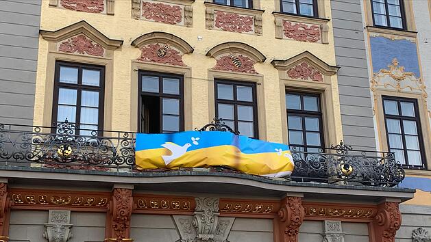 Bis vor kurzem wurde am Balkon des Coburger Rathaus noch fürs Impfen gegen Corona geworben - inzwischen hängt dort eine ukrainische Flagge mit zwei Friedenstauben.