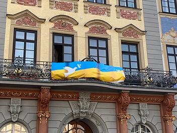 Bis vor kurzem wurde am Balkon des Coburger Rathaus noch fürs Impfen gegen Corona geworben - inzwischen hängt dort eine ukrainische Flagge mit zwei Friedenstauben.