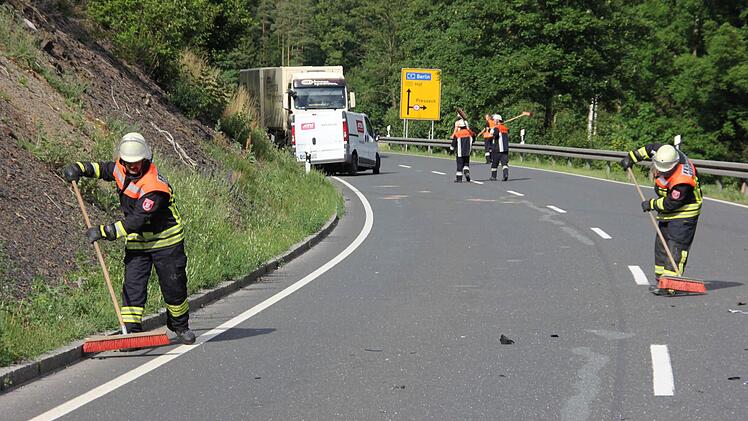 Feuerwehrleute fegten die Trümmer zusammen. Im Hintergrund der stark beschädigte Sprinter.