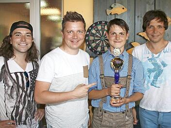 So sieht ein stolzer und strahlender Dart-Sieger aus: Elias (Zweiter von rechts) freut sich über seinen Pokal. Es gratulierten die Kirchaicher "Dorfrocker" (von links) Philipp, Tobias und Markus Thomann. Foto: Ralf Naumann