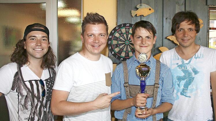 So sieht ein stolzer und strahlender Dart-Sieger aus: Elias (Zweiter von rechts) freut sich über seinen Pokal. Es gratulierten die Kirchaicher "Dorfrocker" (von links) Philipp, Tobias und Markus Thomann. Foto: Ralf Naumann