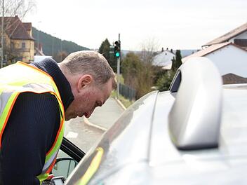 Matthias Stöcker von der Kronacher Polizei spricht durch Autofenster mit einer Verkehrssünderin, die mit Handy am Steuer erwischt worden ist. Foto: Anna-Lena Deuerling