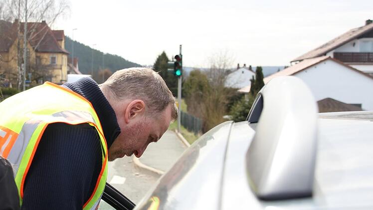Matthias Stöcker von der Kronacher Polizei spricht durch Autofenster mit einer Verkehrssünderin, die mit Handy am Steuer erwischt worden ist. Foto: Anna-Lena Deuerling