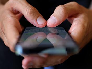 Ein Jugendlicher tippt auf einem Smartphone eine Nachricht.