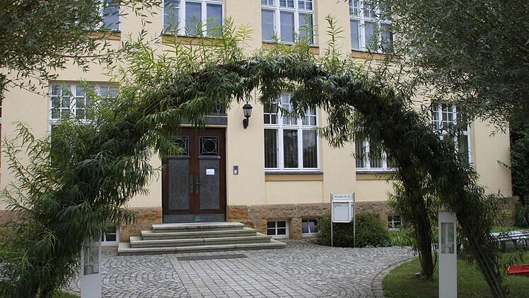 Unter einem Weidenbogen geht man zum Haupteingang der Schule.