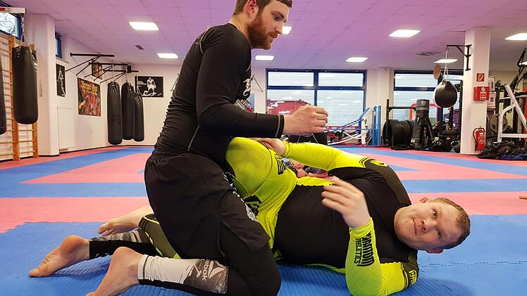 Bj&ouml;rn Schmiedeberg (gelb) erkl&auml;rt Teilnehmer Florian Fuchs, wie man sich aus der "Mount"-Position befreit.  Fotos: privat