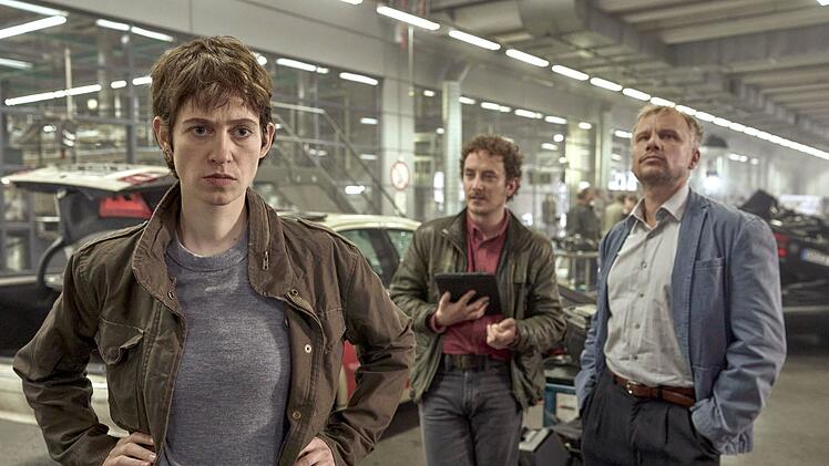Die Ermittler Anne Goldmundt (Lia von Blarer), Hänno Gudjons (David Hugo Schmidt) und Jan Auschra (Robert Stadlober, rechts) arbeiten in einer großen Halle, in der sämtliche Autowracks zu Untersuchungszwecken "aufgebahrt" wurden.