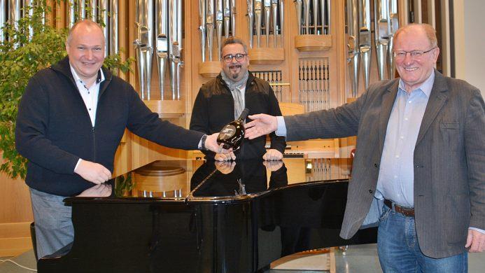 Im Orgelsaal der Berufsfachschule für Musik Bad Königshofen überreichte Schulleiter Professor  Ernst Oestreicher an seinen designieren Nachfolger, Elmar Sebastian Koch (links) einen fränkischen Bocksbeutel zur Begrüßung. Mit auf dem Foto Frank Stäblein, Leiter der Musikschule des Landkreises Rhön-Grabfeld. Foto: Hanns Friedrich