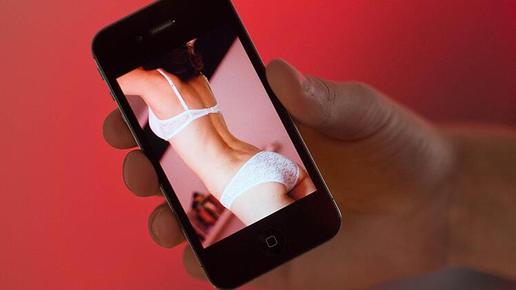 Ein junger Mann hält a in Hannover ein Smartphone, auf dem ein erotisches Foto einer jungen erwachsenen Frau zu sehen ist. Zahlreiche Schulleiter aus Cloppenburg warnen in einem gemeinsamen Elternbrief vor dem neuen Trend «Sexting». Dabei versenden Jugendliche erotische Fotos oder Nacktbilder von sich per Smartphone an Freunde oder laden sie in sozialen Netzwerken hoch. Foto: Julian Stratenschulte/dpa