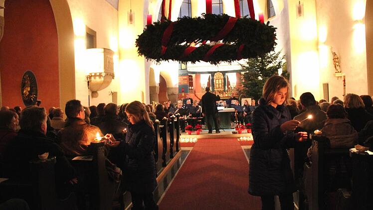 Kinder zünden die Kerzen in den Schiffchen an.