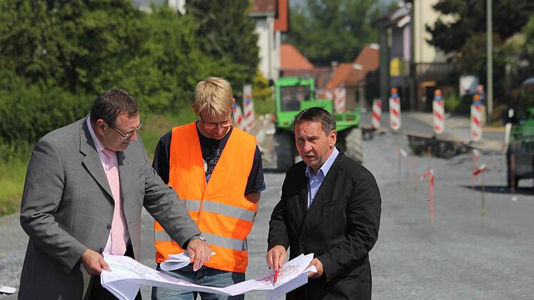 Siegfried Beck vom Bauamt, Jörg Döhler von der Baufirma Rädlinger und Bürgermeister Norbert Gräbner (von links) an der Baustelle bei Seibelsdorf. Im Hintergrund wird am neuen Gehweg gearbeitet.