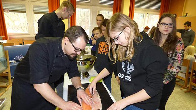 Der stellvertretende K&uuml;chenchef des G&ouml;&szlig;weinsteiner Hotels Stempferhof zeigt Sarah Feigl aus Tr&auml;gweis wie man einen Lachs richtig filetiert. Foto: Thomas Weichert
