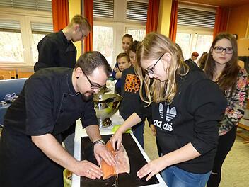Der stellvertretende Küchenchef des Gößweinsteiner Hotels Stempferhof zeigt Sarah Feigl aus Trägweis wie man einen Lachs richtig filetiert. Foto: Thomas Weichert