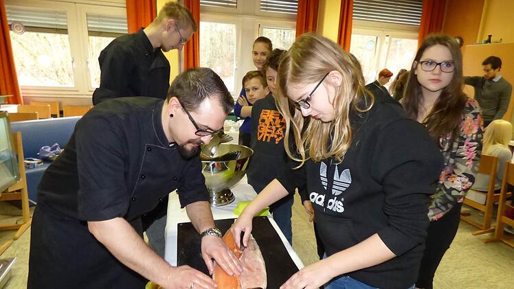 Der stellvertretende Küchenchef des Gößweinsteiner Hotels Stempferhof zeigt Sarah Feigl aus Trägweis wie man einen Lachs richtig filetiert. Foto: Thomas Weichert