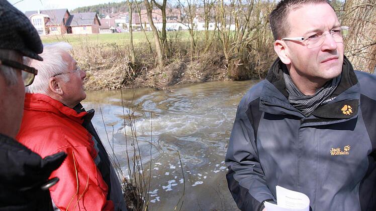 Die Adelsdorfer Gemeinderäte Erwin Kotzer, Klaus Keil und Bürgermeister Karsten Fischkal (von links) schauen skeptisch: Unter der Aisch ist ein Rohr gebrochen. Die Leitung ist trocken gelegt. Der Luftdruck-Test verwandelt die Aisch in einen reißenden Strudel. Fotos: Sebastian Martin