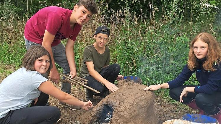 Rosa Kneuer, Jonas Bühl, Andreas Kundmüller und Anika Berninger (von links) befeuern den selbst gebauten Lehmbackofen.