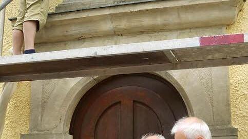 Steinrestaurator und Meister im Steinmetz- und Steinbildhauerhandwerk, Wilhelm Keim (auf dem Gerüst) hat mit der Restaurierung des Wappensteins am Westportal der Heilig Dreifaltigkeitskirche in Theisenort begonnen. Mit im Bild Kirchenpfleger Heinz Kraus (rechts) und Günther Dobner (Kirchenveraltungsmitglied). Foto: K.-H. Hofmann