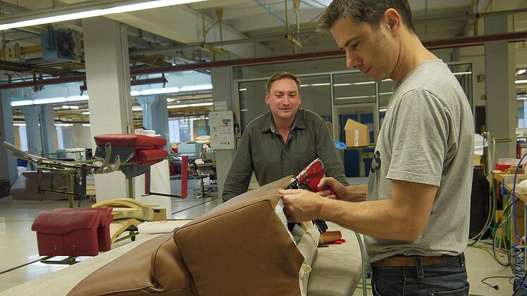 Als Leiter der Qualitätssicherung schaut Swen Hoese (links) auch immer wieder mal in der Polsterei vorbei - wie hier bei seinem Kollegen Thomas Schäfer, der auch schon über zwei Jahrzehnte Erfahrung als Polsterer hat. Foto: Berthold Köhler