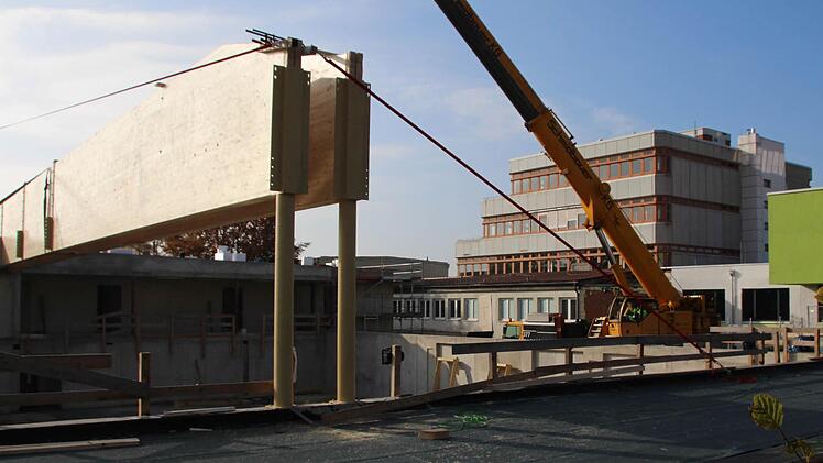 Während der Kollegstufenbau des Gymnasiums (im Hintergrund) auf eine Sanierung wartet, wird an der neuen Sporthalle (vorne) der Dachstuhl aufgerichtet. Foto: Andreas Dorsch