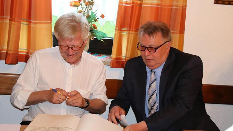 Bürgermeister Willi Sendelbeck legt dem Bischof das goldene Buch vor.