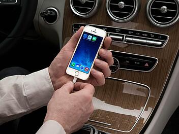 Ein Mann schließt in einem Wagen der neuen Mercedes-Benz C-Klasse ein iPhone an. Mit dem neuen System CarPlay, das iPhone und Navigationssystem des Autos verbindet, ist es möglich, Musik zu hören, zu navigieren, Nahcrichten zu empfangen und zu telefonieren. Foto:  Mercedes-Benz/dpa