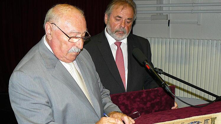 Der Pilisszentivaner Bürgermeister Gabor Penzes unterzeichnet die Bekräftigung der Partnerschaft, rechts sein Kollege aus Marktleugast, Norbert Volk.