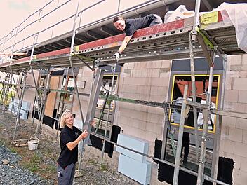 Frauenpower auf der Baustelle des Kindergartens "Mäuseparadies": Andrea Lattner reicht Carina Hofmann auf dem Gerüst Material nach oben.