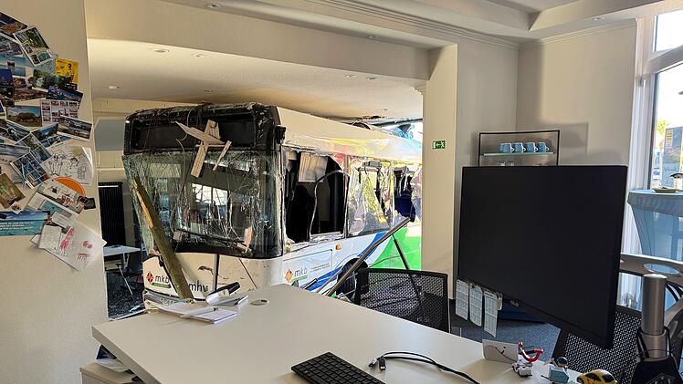 Bus kollidiert mit Auto und kracht in Reisebüro
