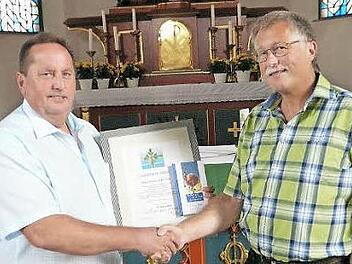 Pfarrgemeinderats-Vorsitzender Norbert Herrmann (links) verabschiedete seinen Vorgänger Klaus Schramm (rechts) und überreichte ihm als Dank für seine Arbeit ein Geschenk. Foto: Klaus-Peter Wulf