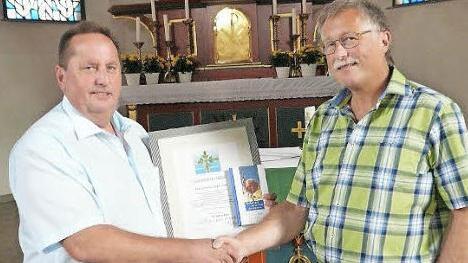 Pfarrgemeinderats-Vorsitzender Norbert Herrmann (links) verabschiedete seinen Vorgänger Klaus Schramm (rechts) und überreichte ihm als Dank für seine Arbeit ein Geschenk. Foto: Klaus-Peter Wulf