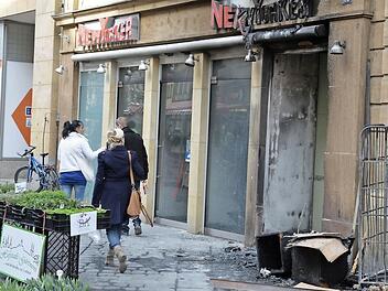 Auslöser des Laden-Brands: In den Gitterboxen (rechts) stand am frühen Dienstagmorgen Altpapier in Flammen. Die Polizei ermittelt nun wegen Brandstiftung.  Foto: Ronald Rinklef