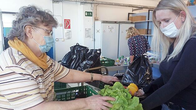 Brigitte K&ouml;rner (links) und Stefanie Renner packen gemeinsam eine T&uuml;te mit Lebensmitteln. Aus Hygienegr&uuml;nden k&ouml;nnen die Kunden aktuell nicht mehr in die R&auml;ume der Tafel. Sie bekommen die verpackten Rationen am Eingang ausgeh&auml;ndigt.  Foto: privat
