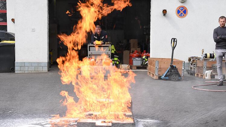 Hinter den Flammen bedient der Feuerwehrmann den FireTrainer.