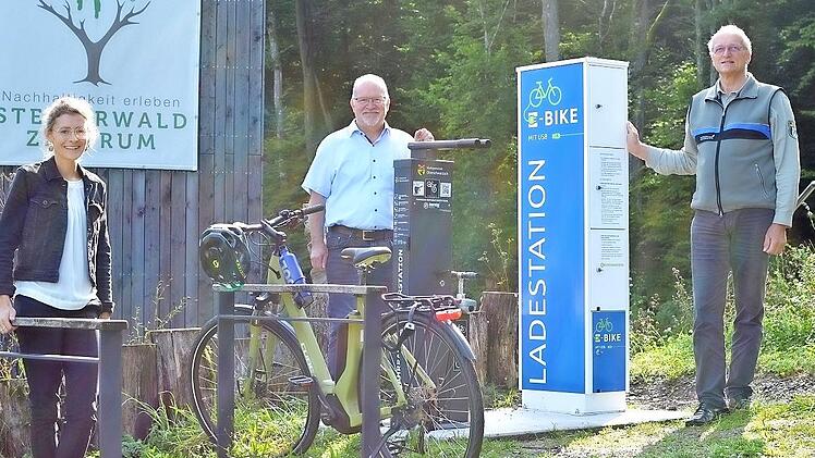 Constanze Stern, Geschäftsleiterin des Trägervereins Steigerwald-Zentrum, Manfred Schötz, Bürgermeister der Marktgemeinde Oberschwarzach, Andreas Leyrer, forstlicher Leiter Steigerwald-Zentrum, bei der E-Bike-Ladestation