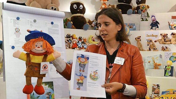 Josephine Dransfeld erklärt (unter Einhaltung von genügend Abstand) anhand einer Puppe für eine kleine Theatergruppe, wie ein Kundenwunsch für ein neues Produkt gut vorbereitet bei Heunec ankommen kann - was nicht immer der Fall ist. Foto: Rainer Lutz