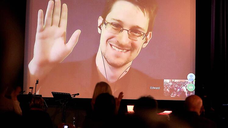 Der NSA-Enthüller Edward Snowden winkt am 14.12.2014 in Berlin während einer Videoschalte dem Publikum zu. Foto: Wolfgang Kumm/dpa