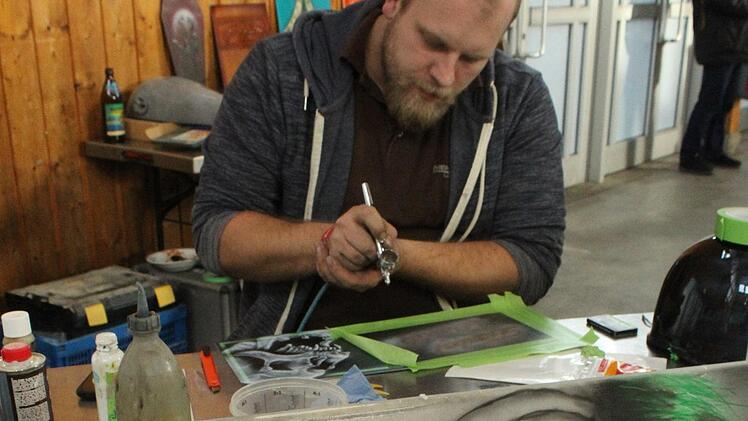 Julian Hümmer aus Waischenfeld sorgt mit Airbrush für auffällige Motive. Mit dem Joker vor ihm wird er selbst zu einem solchen. Foto: Markus Häggberg